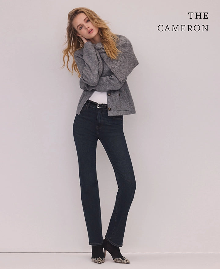 A blonde woman in a gray blazer and dark jeans poses against a plain white background with "THE CAMERON" text in the upper right corner.