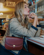 Veronica Beard Burgundy leather saddle bag with gold clasp.