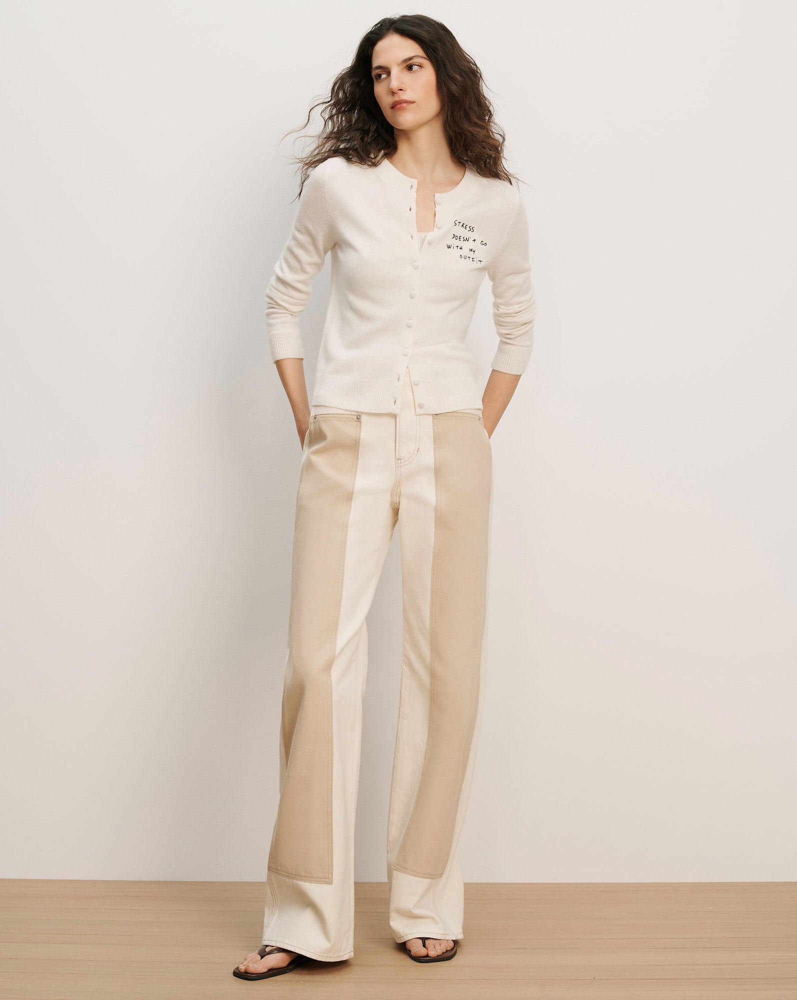 Veronica Beard Cream button-front cardigan with black text on the chest and two-tone beige wide-leg trousers.