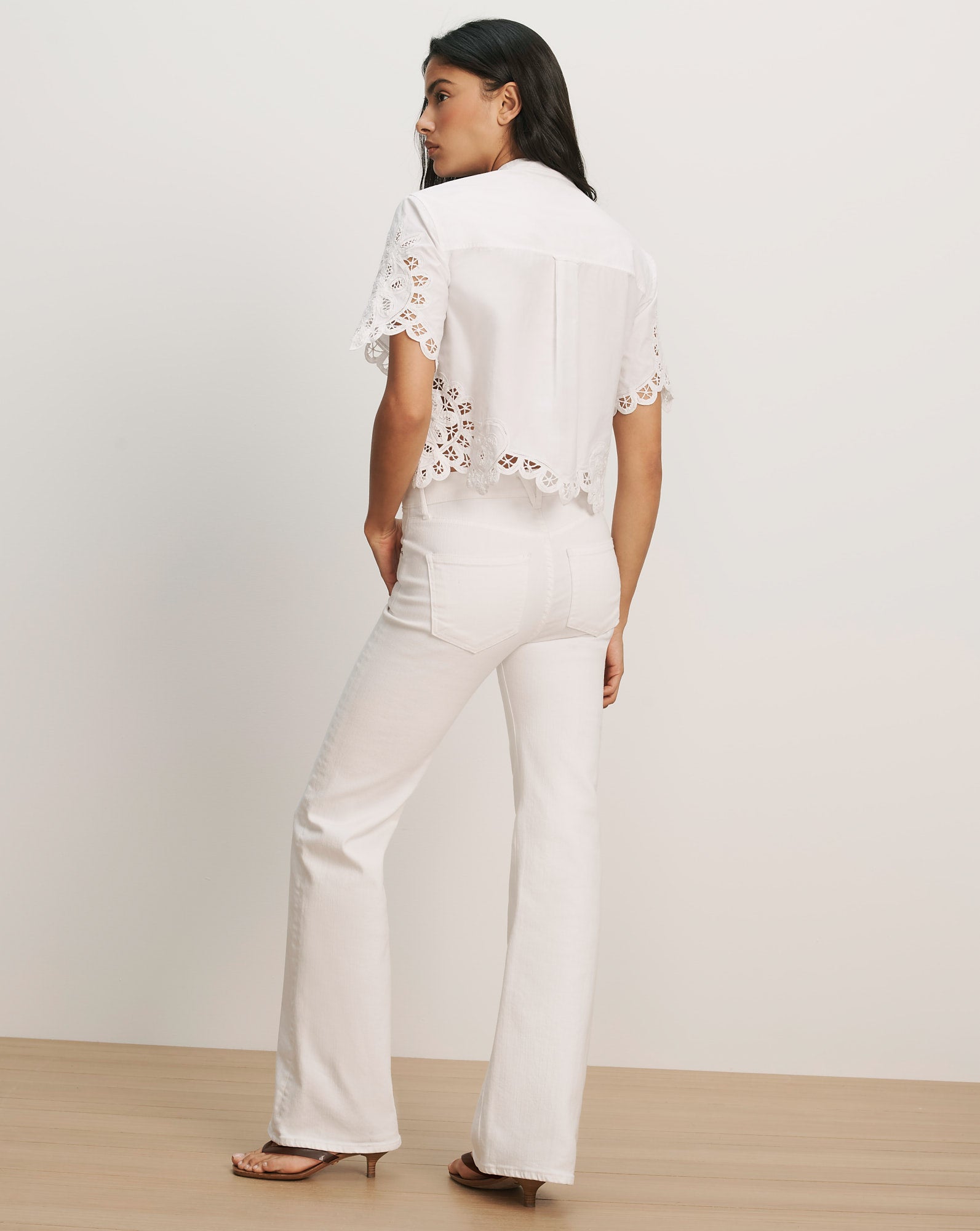 Veronica Beard White eyelet lace short-sleeve button-up shirt with scalloped hem and white flare jeans.
