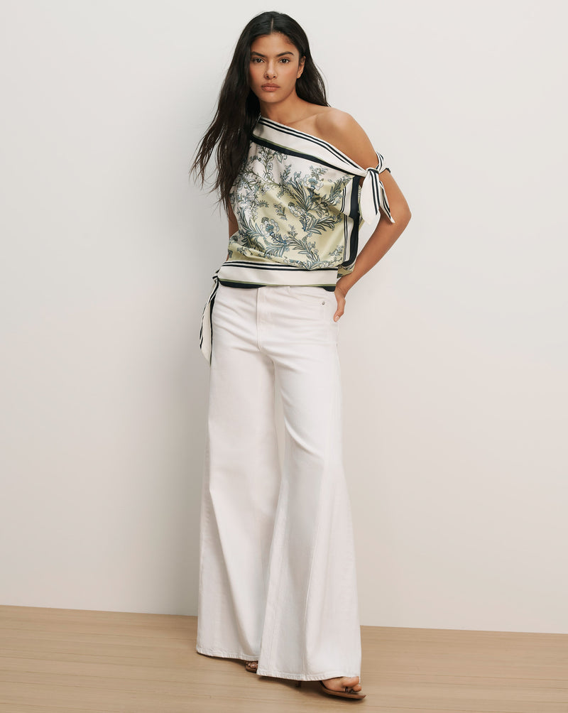 Veronica Beard Off-the-shoulder silk top with a green and white floral print, black trim, and white wide-leg pants.