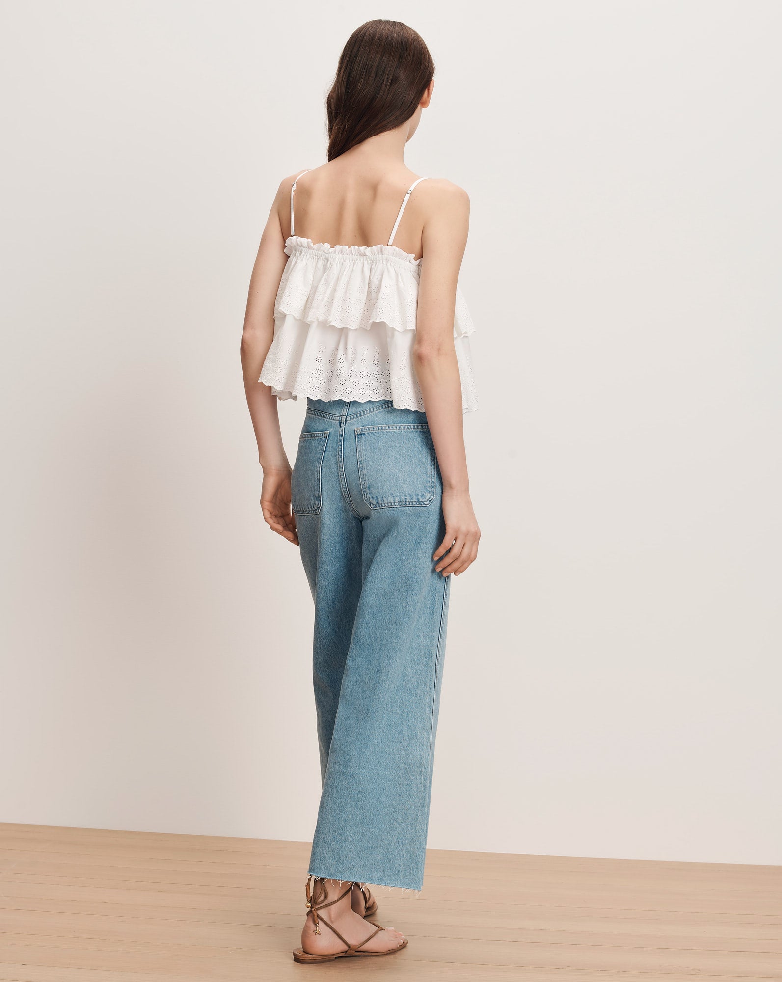 Veronica Beard White tiered ruffle camisole with spaghetti straps and light wash wide-leg jeans.