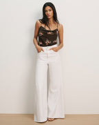 Veronica Beard Black floral print camisole with spaghetti straps and white wide-leg jeans.