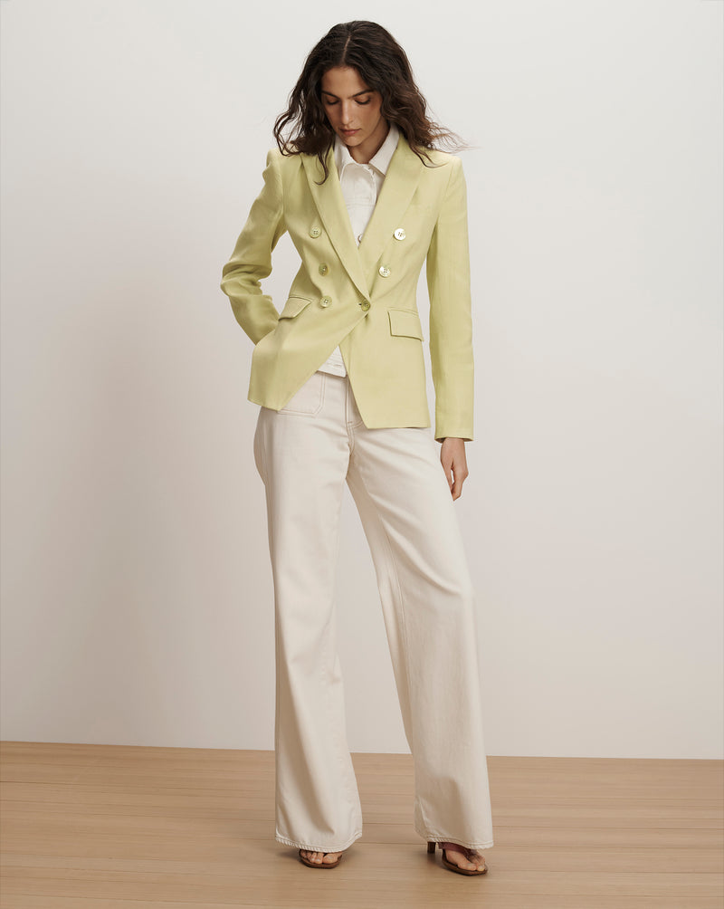 Veronica Beard Light green double-breasted blazer with peak lapels, paired with a white collared shirt and cream wide-leg trousers.