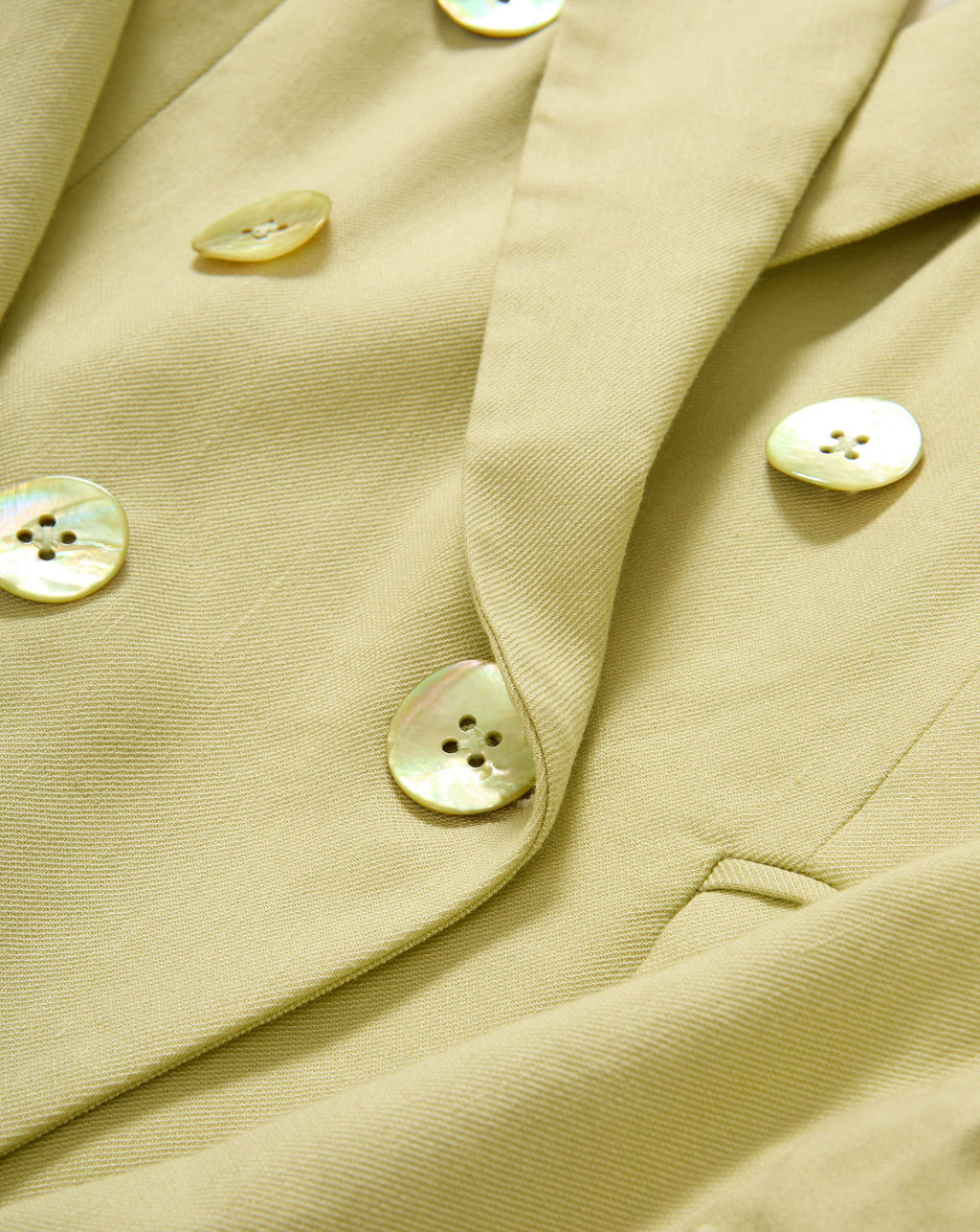 Veronica Beard Light green double-breasted blazer with peak lapels, paired with a white button-down shirt and off-white trousers.