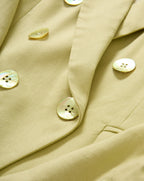 Veronica Beard Light green double-breasted blazer with peak lapels, paired with a white button-down shirt and off-white trousers.