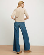 Veronica Beard Beige knit short-sleeve sweater and wide-leg blue jeans.