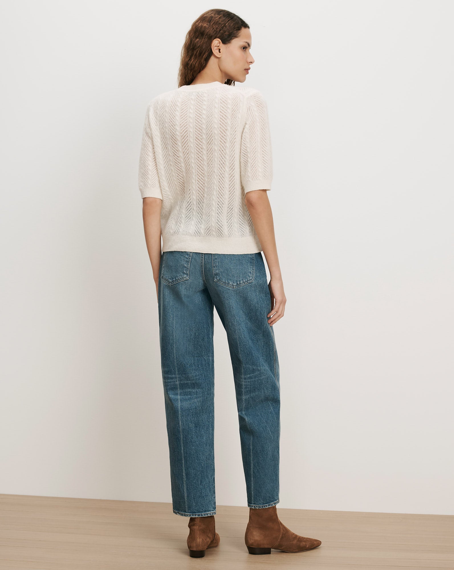 Veronica Beard White knit short-sleeve sweater and blue jeans.