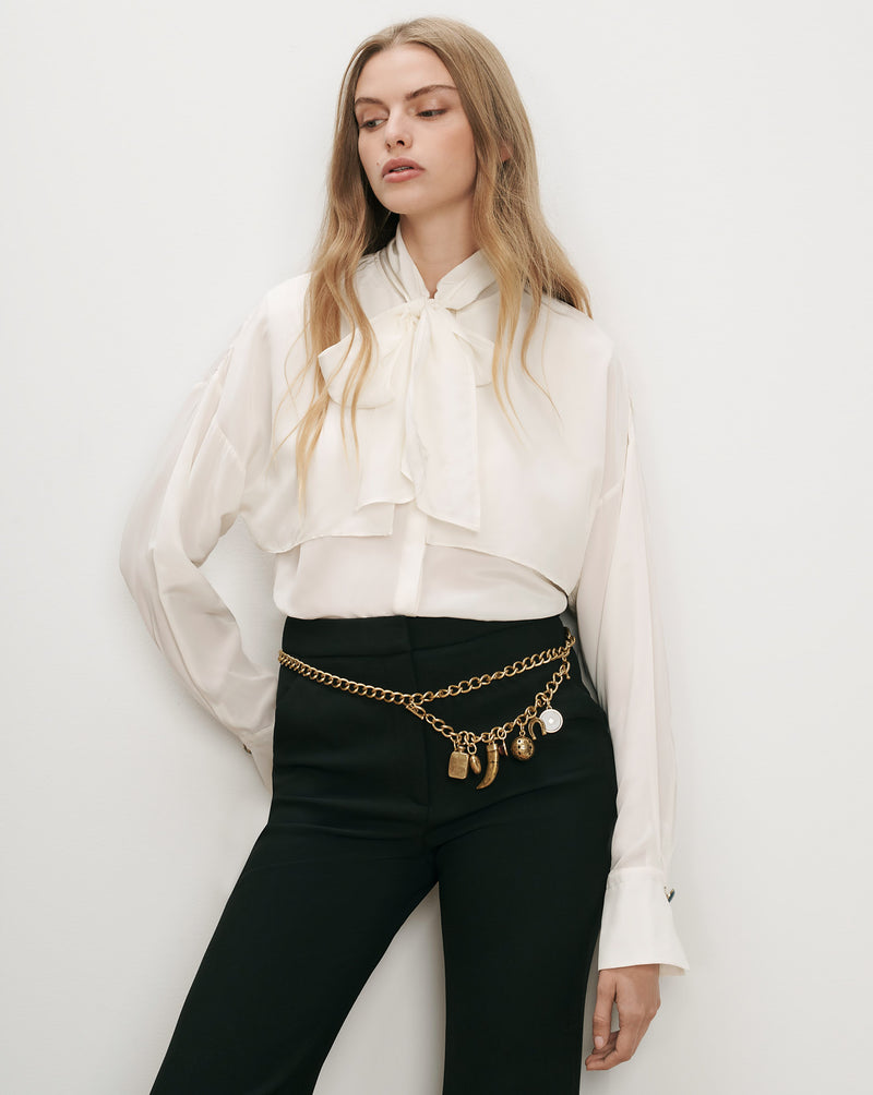 Veronica Beard White silk blouse, black trousers, gold chain belt.