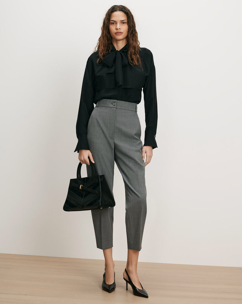 Veronica Beard Black silk blouse, gray trousers, black heels, black handbag.