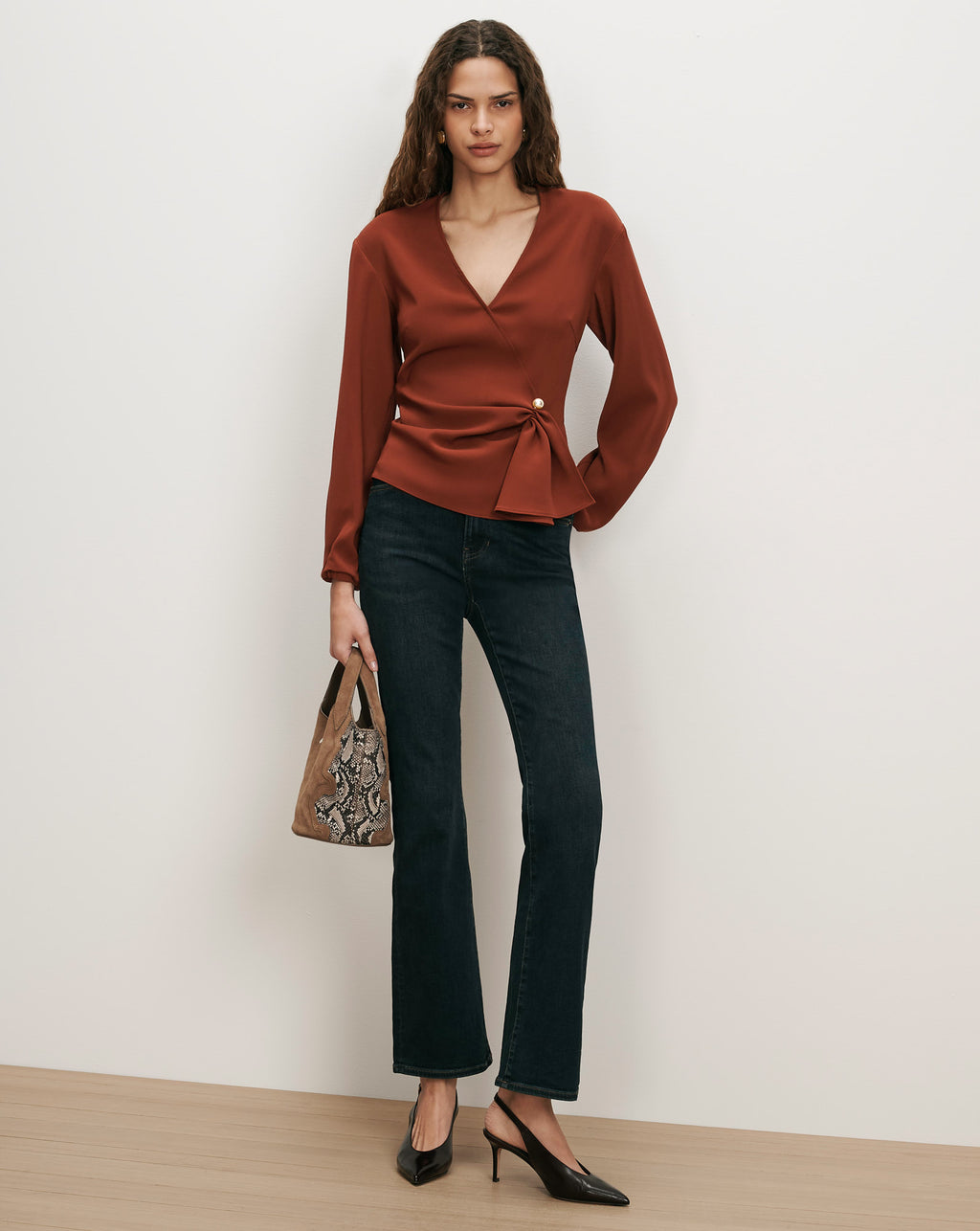 Veronica Beard Brown wrap blouse with gold button, dark wash jeans.