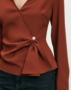Veronica Beard Rust wrap blouse with pearl button detail.