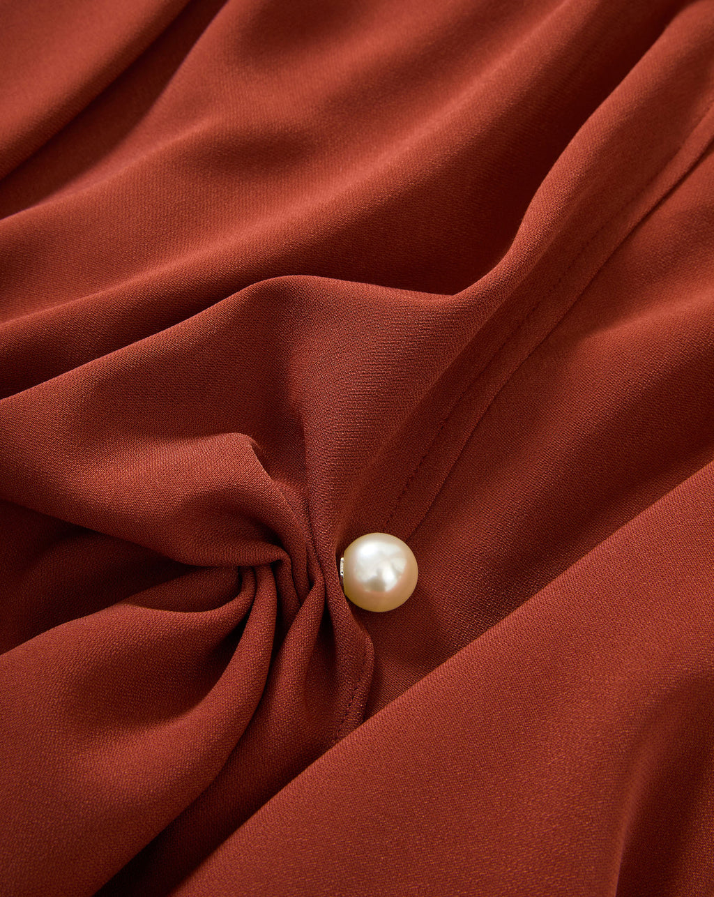 Veronica Beard Rust blouse, draped, with a pearl button.