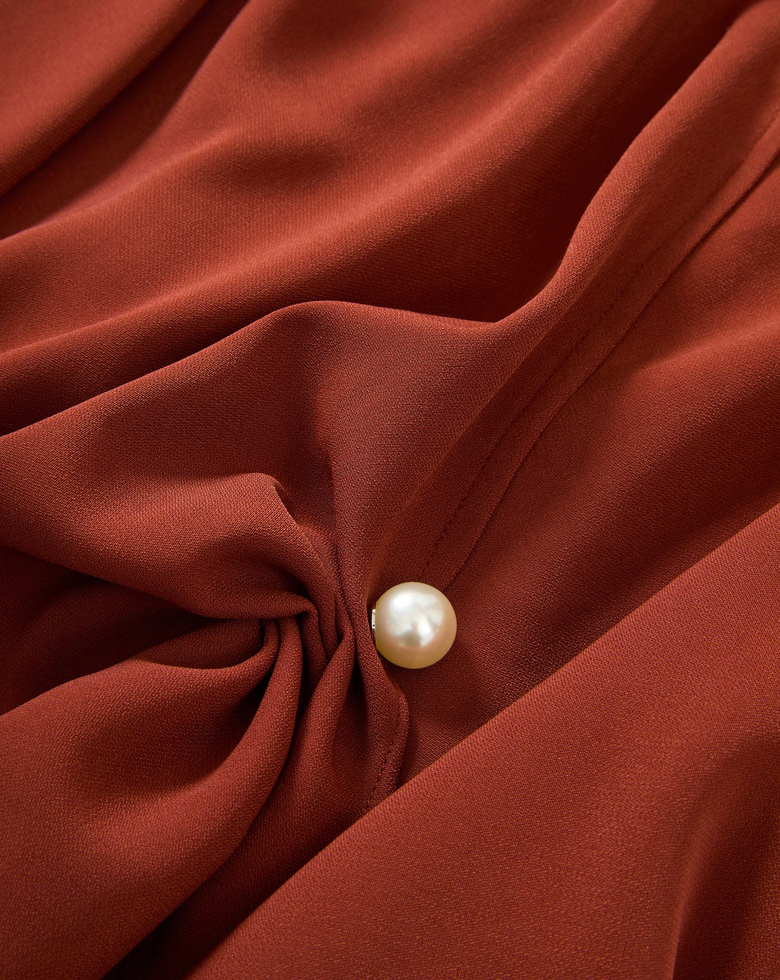 Veronica Beard Rust blouse, draped, with a pearl button.
