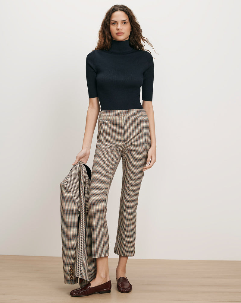 Veronica Beard Black ribbed turtleneck, brown plaid pants, brown loafers.