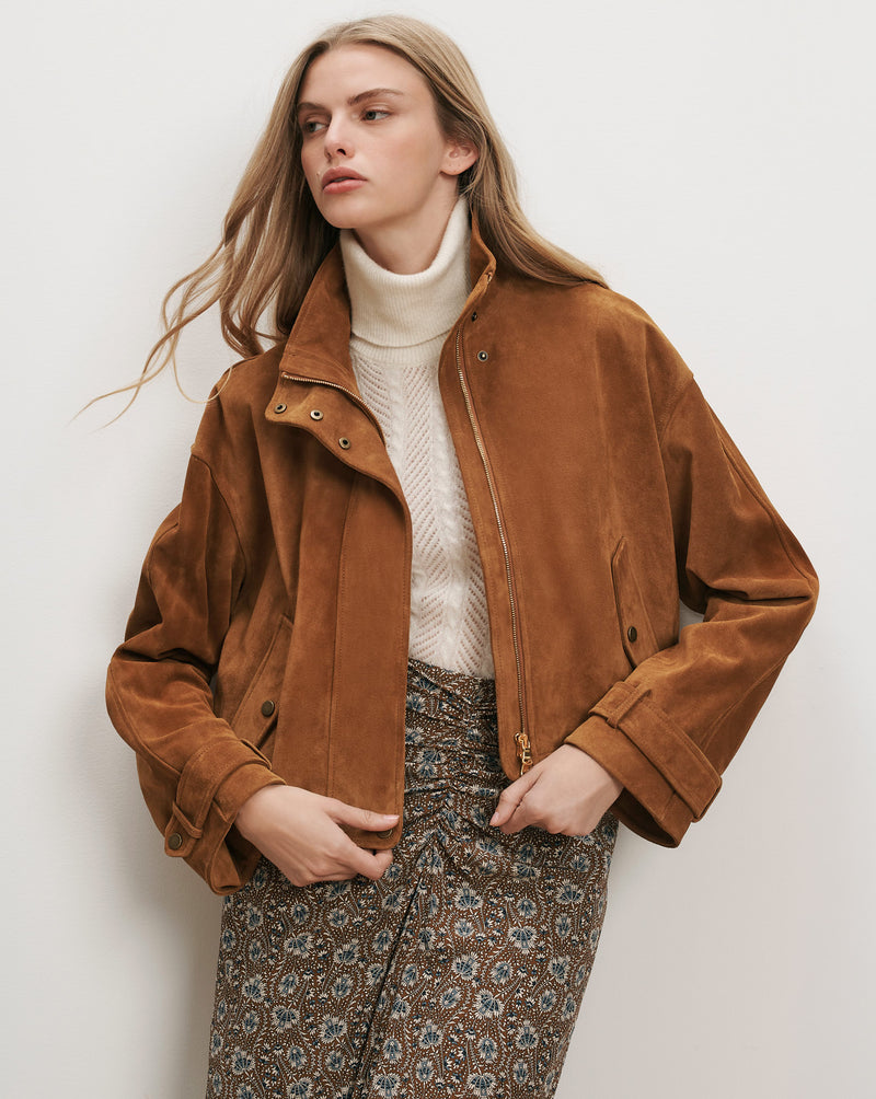 Veronica Beard Brown suede bomber jacket with a white turtleneck.