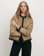 Veronica Beard Tan quilted jacket with black trim and buttons.