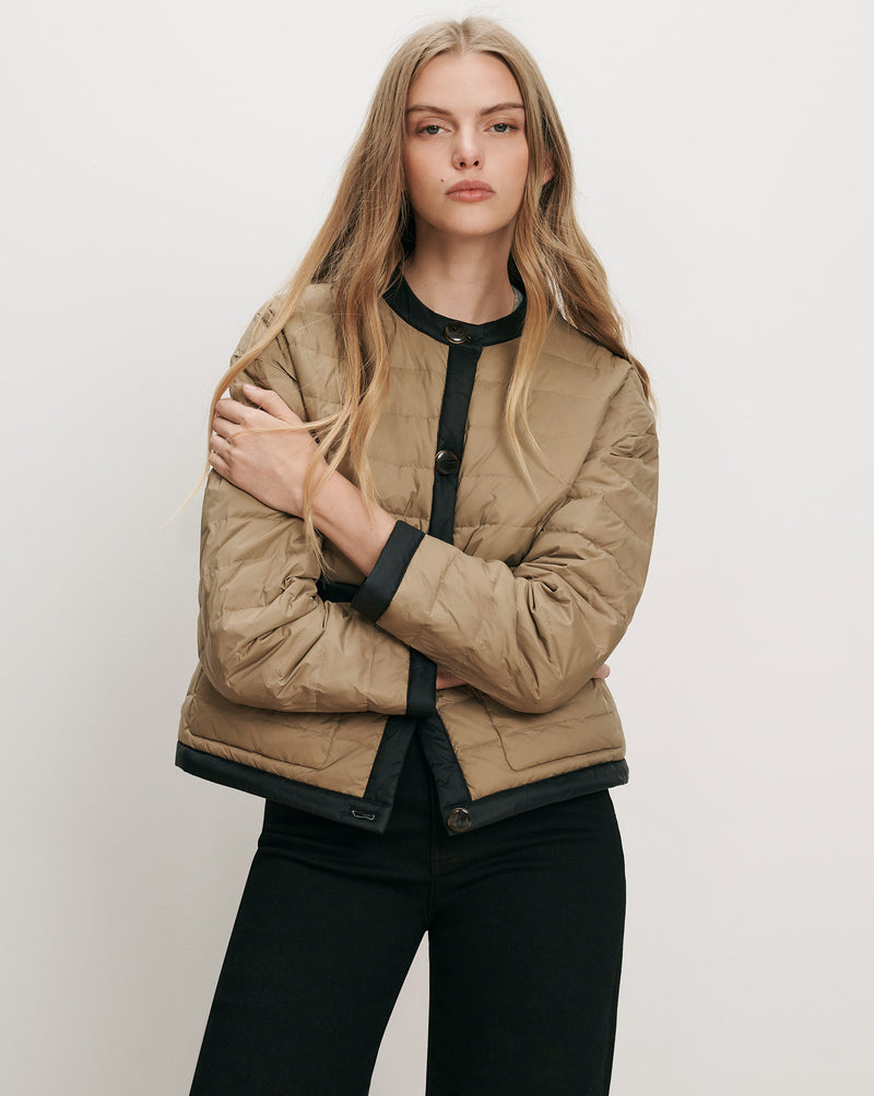 Veronica Beard Tan quilted jacket with black trim and buttons.