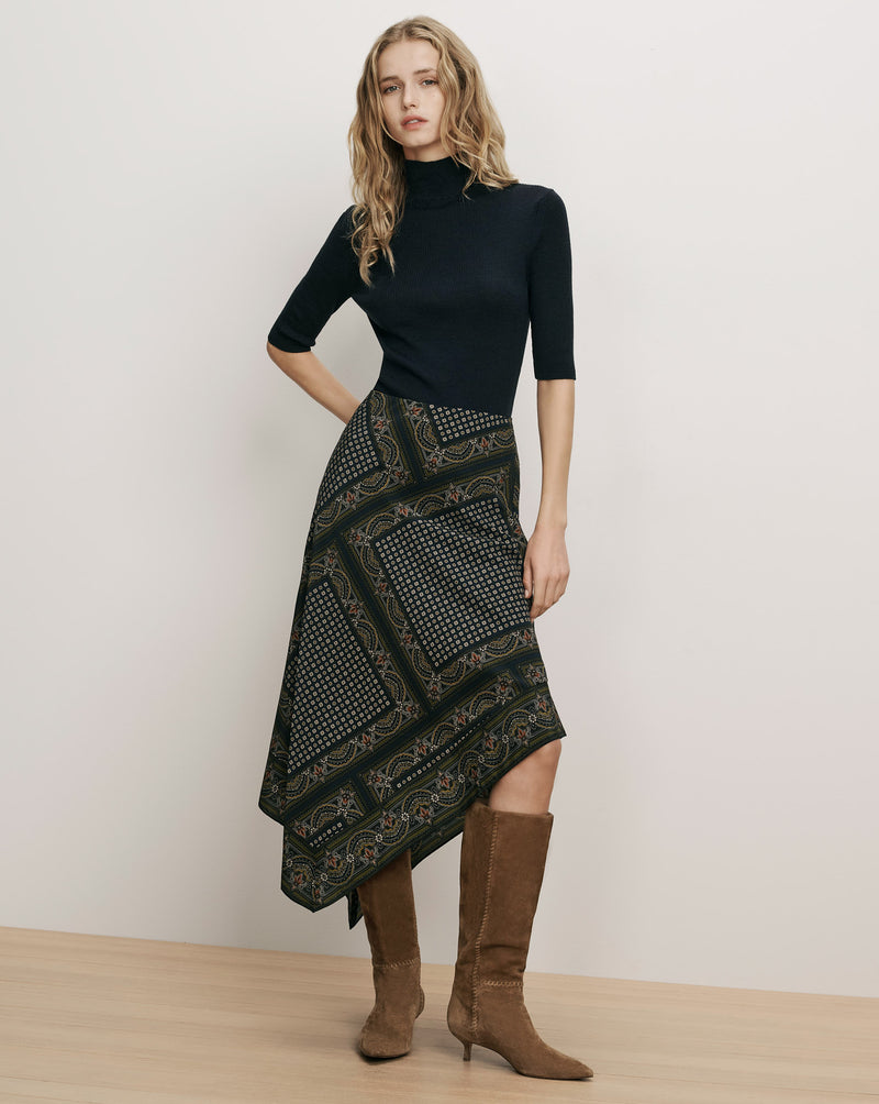 Veronica Beard Black ribbed turtleneck, patterned handkerchief hem skirt, brown suede boots.