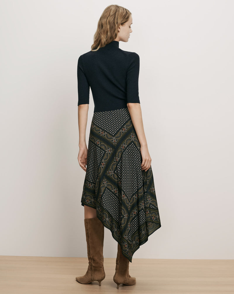 Veronica Beard Black ribbed top, patterned handkerchief skirt, brown suede boots.