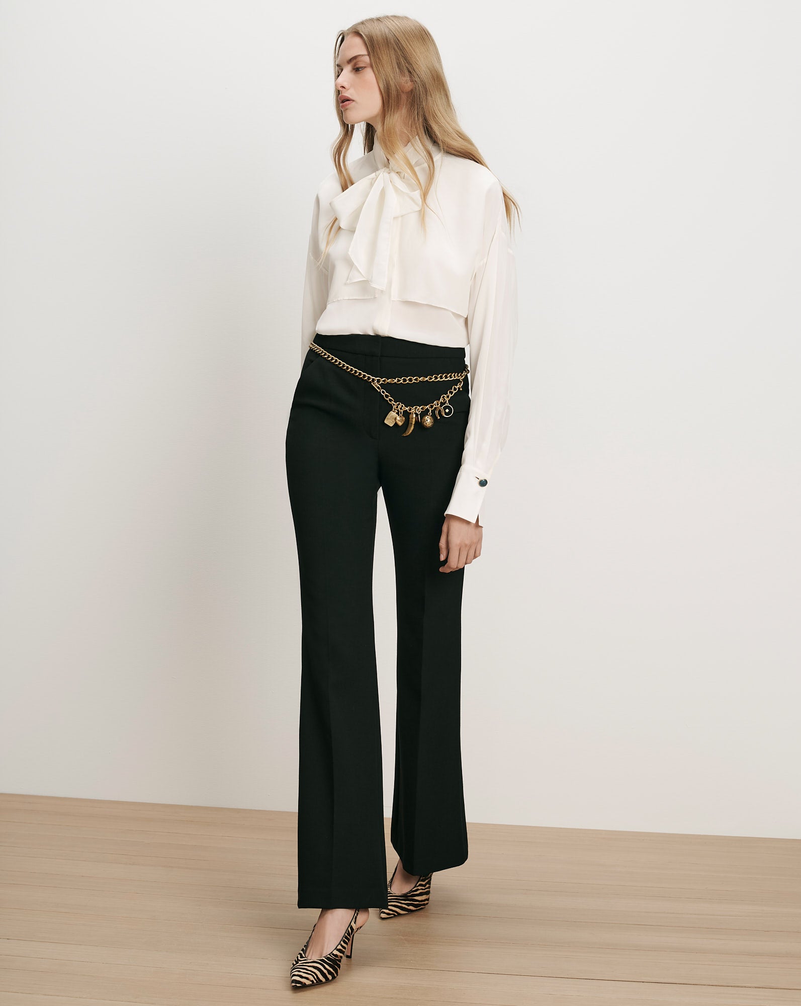 Veronica Beard White silk blouse, black flared trousers, gold chain belt.