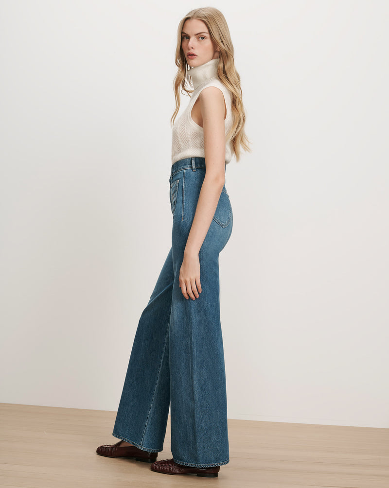 Veronica Beard White sleeveless turtleneck sweater, blue wide-leg jeans
