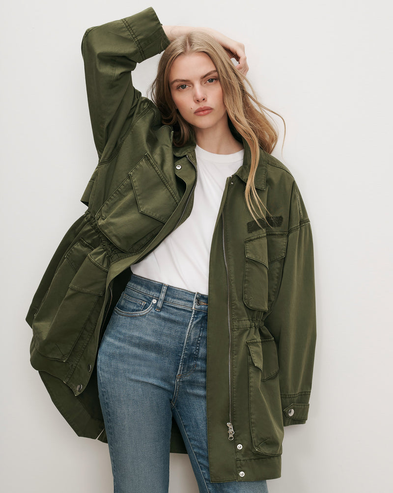 Veronica Beard Olive green utility jacket, white t-shirt, blue jeans.
