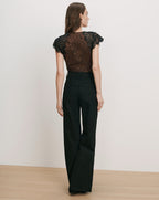 Veronica Beard Black lace top and black wide-leg jeans.