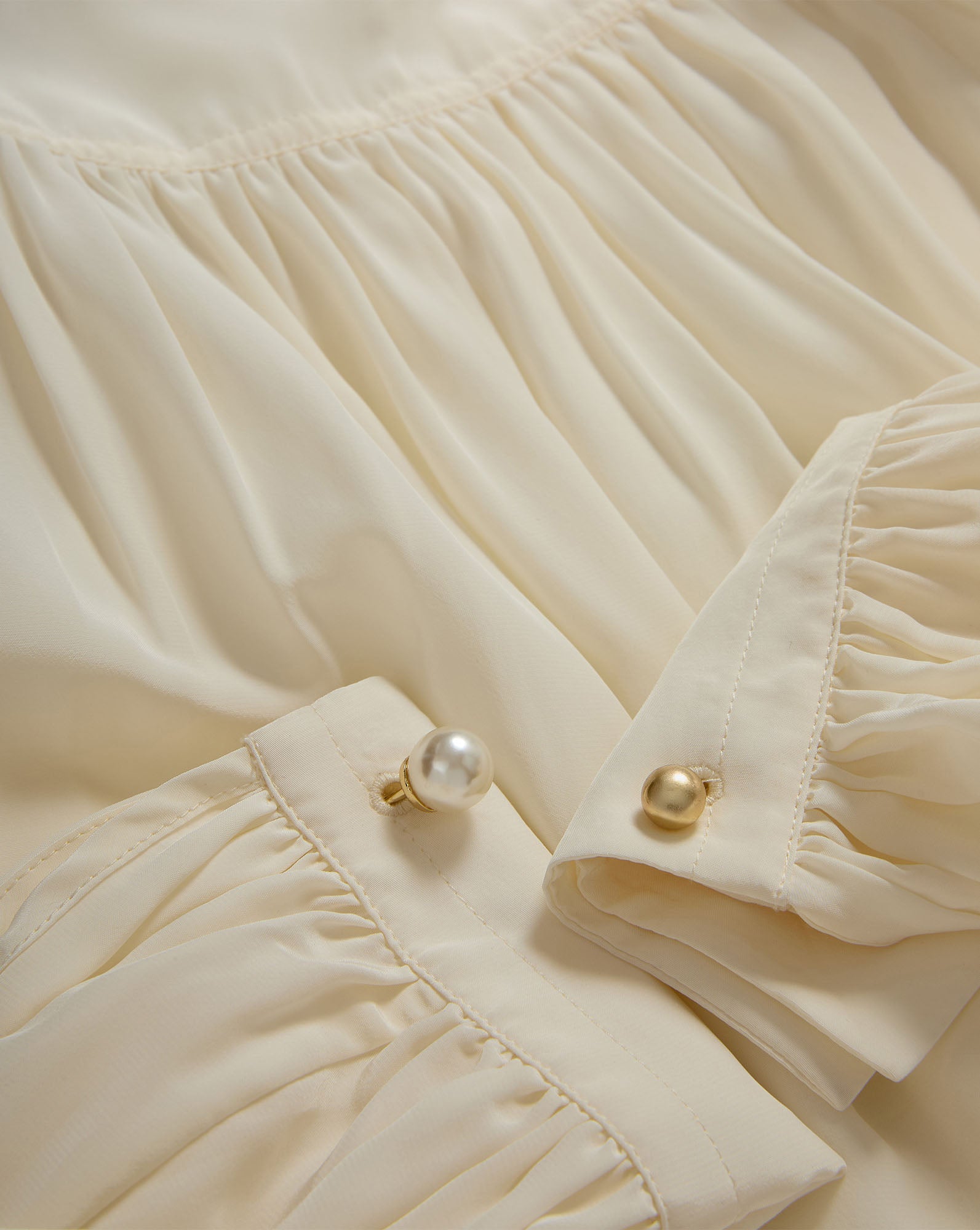 Veronica Beard Cream pleated blouse with pearl and gold buttons.