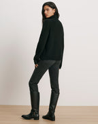 Veronica Beard Black turtleneck sweater, dark wash jeans, black leather boots.