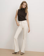 Veronica Beard Brown sleeveless turtleneck top and white flare jeans.