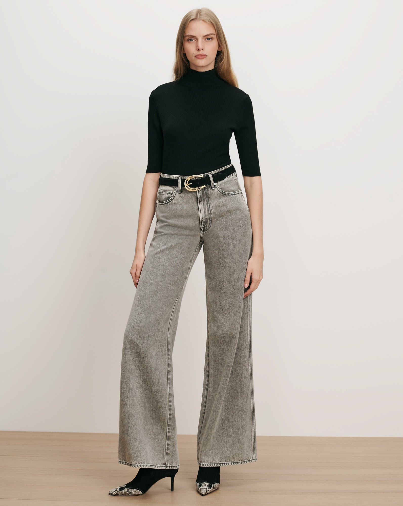 Veronica Beard Black ribbed turtleneck, gray wide-leg jeans, black belt.