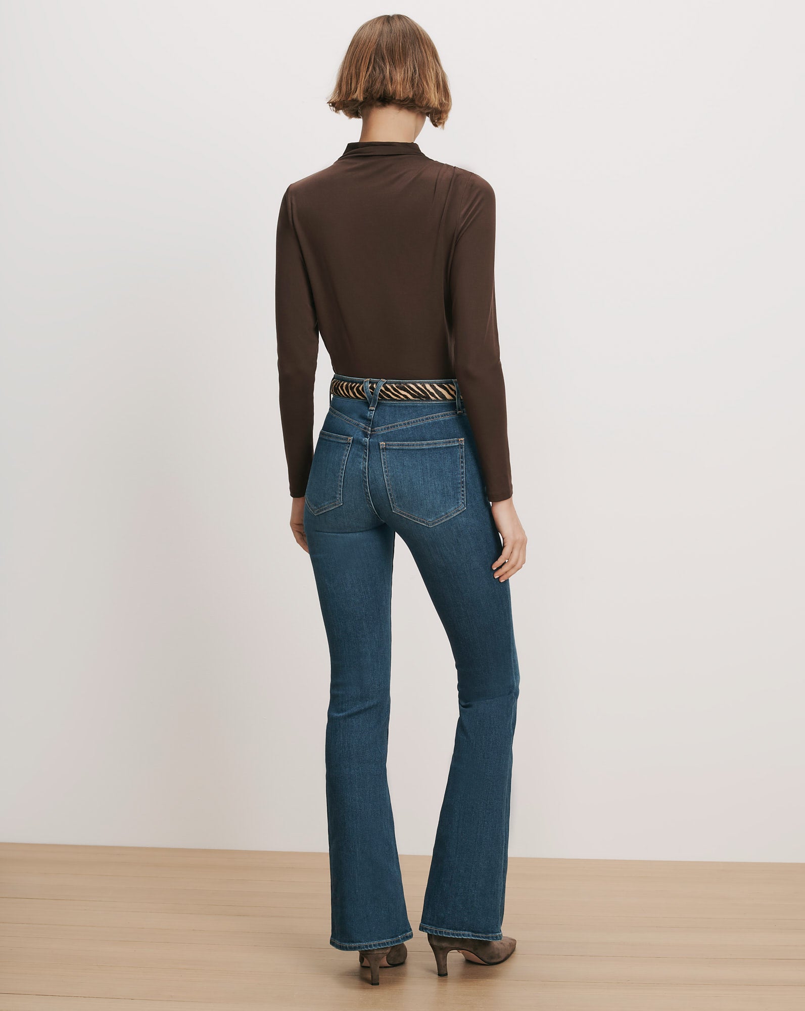 Veronica Beard Brown long-sleeve top, blue flare jeans, zebra belt
