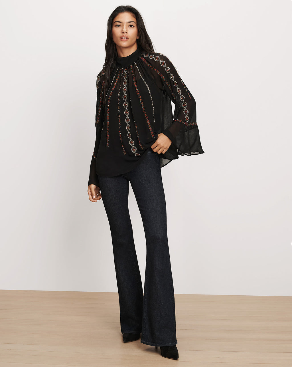 Veronica Beard Black embroidered sheer blouse and flared jeans.