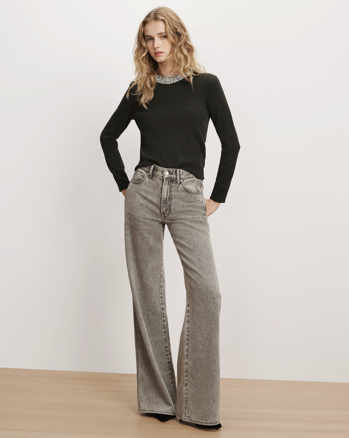 Veronica Beard Black embellished sweater and grey wide-leg jeans.