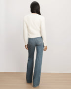 Veronica Beard White knit sweater and blue flare jeans.