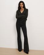 Veronica Beard Dark green V-neck sweater and black patterned flare jeans.