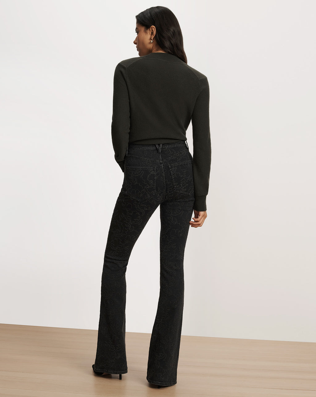 Veronica Beard Black patterned flare jeans and dark green sweater.