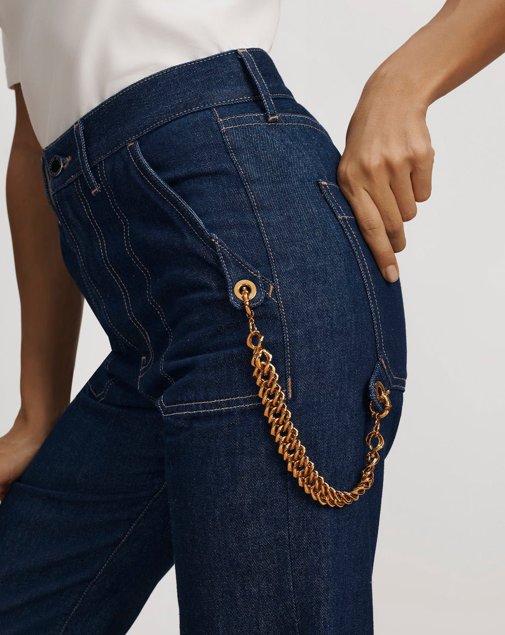 Veronica Beard Dark blue denim high-waisted jeans with gold chain.