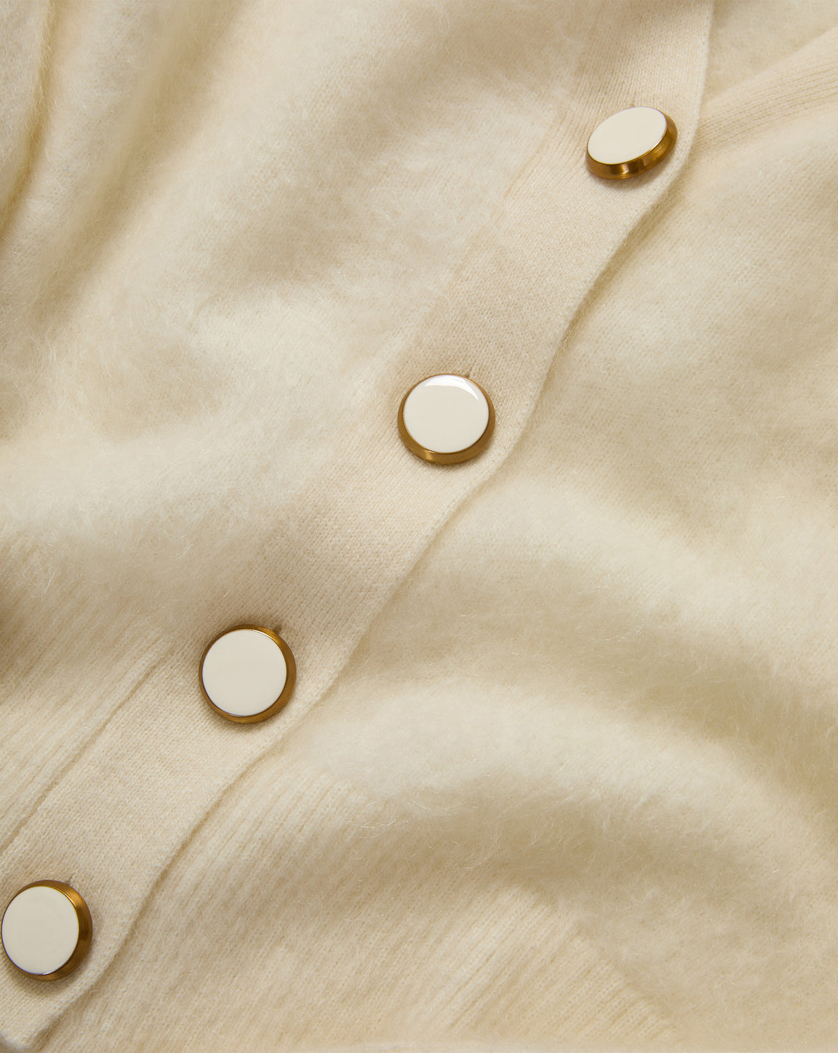 Veronica Beard Cream knit cardigan with gold-rimmed white buttons.