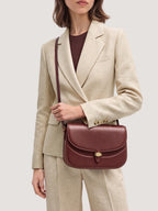 Veronica Beard Structured burgundy leather crossbody bag with clasp closure.
