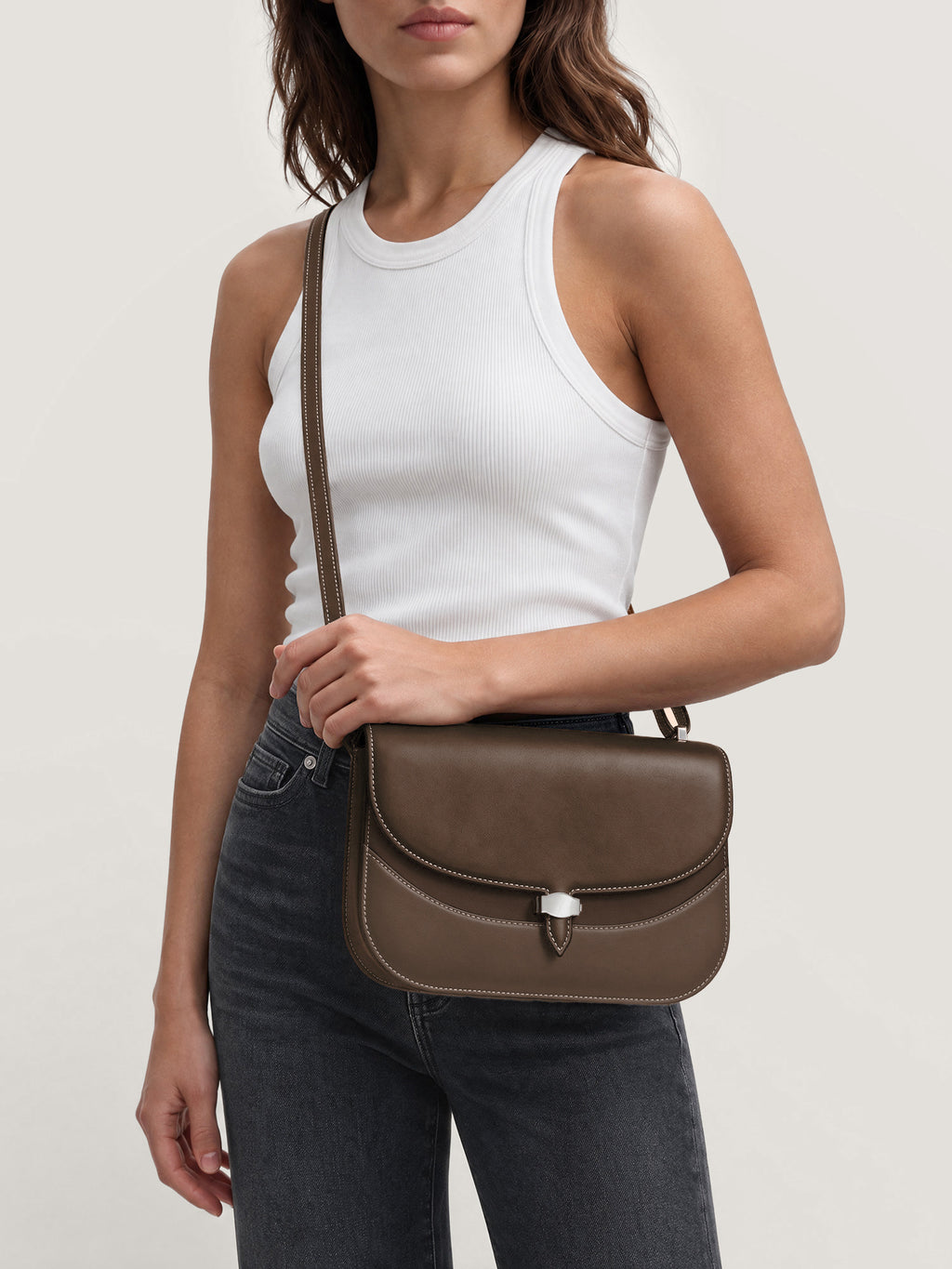 Veronica Beard Brown leather saddle crossbody bag with white stitching.