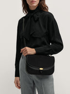 Veronica Beard Black blouse with pussy bow, grey trousers.