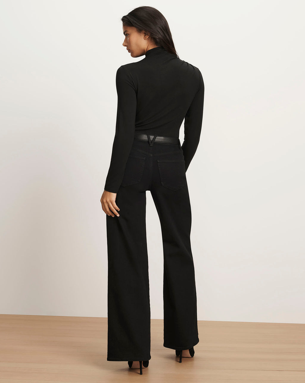 Veronica Beard Black long-sleeve turtleneck top and black wide-leg jeans.