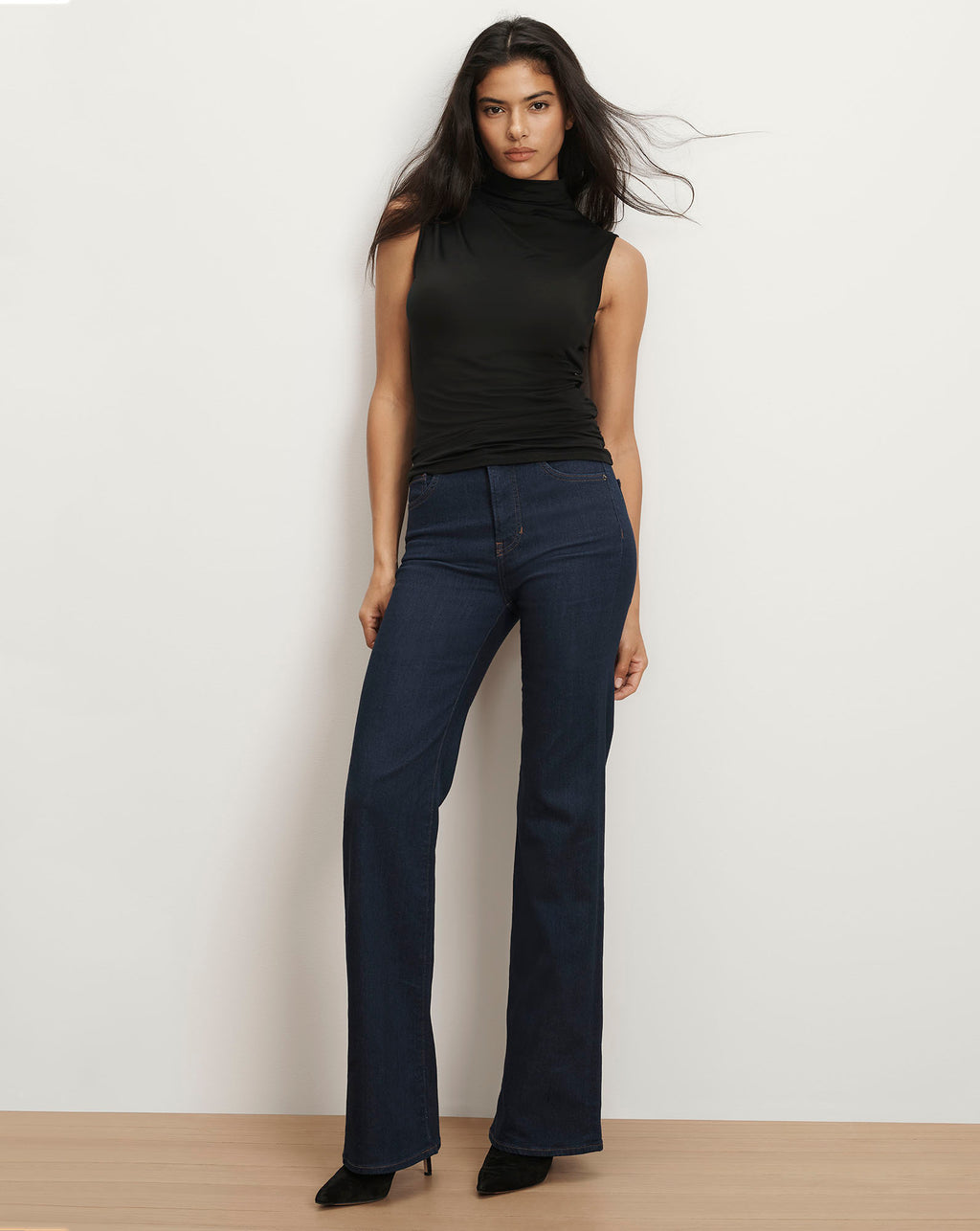 Veronica Beard Black sleeveless turtleneck top and dark wash flare jeans.