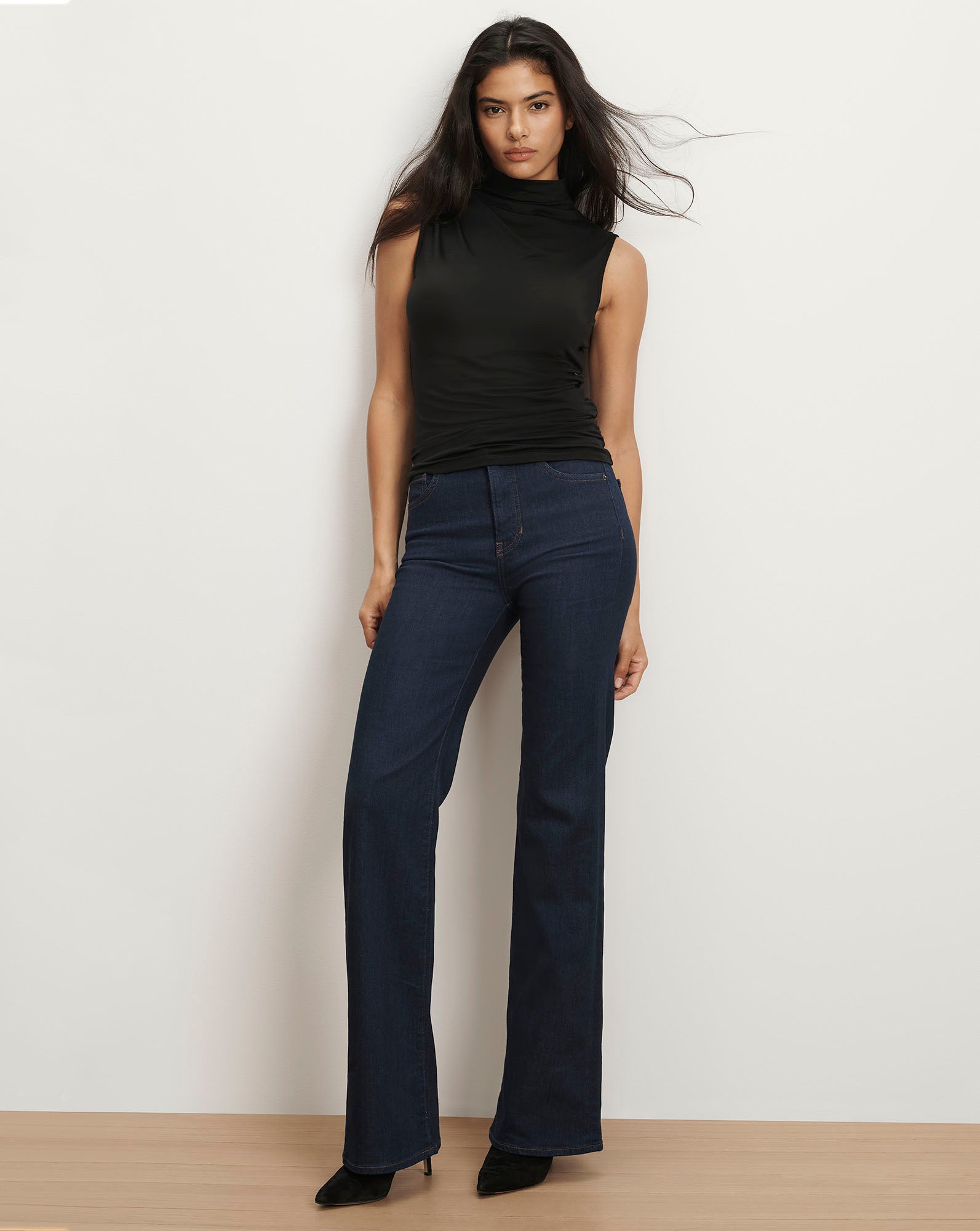 Veronica Beard Black sleeveless turtleneck top and dark wash flare jeans.