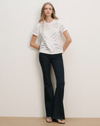 Veronica Beard White short-sleeve t-shirt with black text print and dark wash flared jeans.