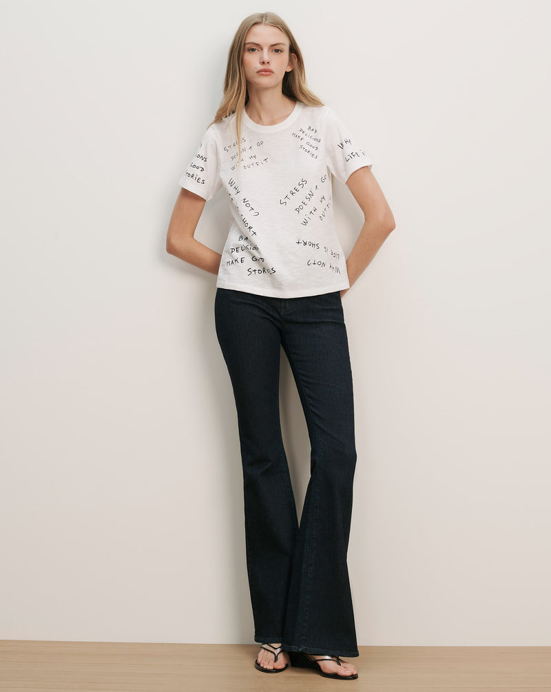 Veronica Beard White short-sleeve t-shirt with black text print and dark wash flared jeans.
