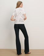 Veronica Beard White short-sleeve t-shirt with black text graphics on the back, paired with dark wash flare jeans.