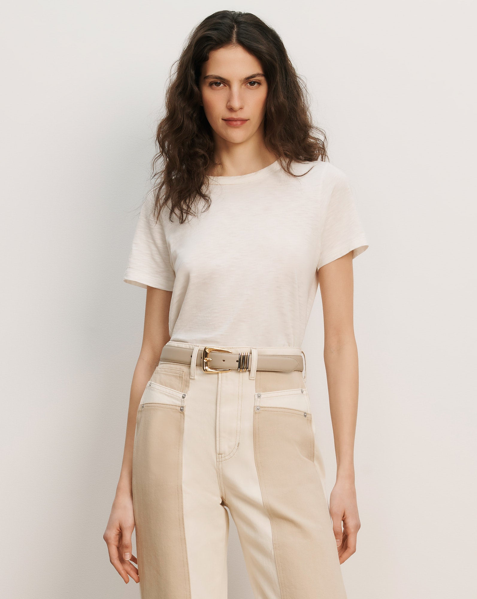 Veronica Beard Cream short-sleeve t-shirt and two-tone beige and cream high-waisted pants with a light beige belt.